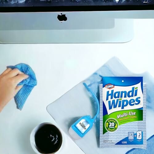 Hand cleaning a desk with Handi Wipes and a small cleaning spray bottle.