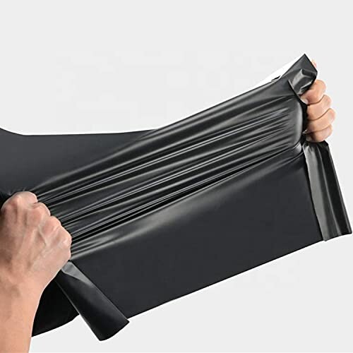 Hands stretching a black plastic sheet.